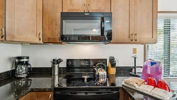 Una cocina con armarios de madera, un microondas, una estufa y una cafetera.