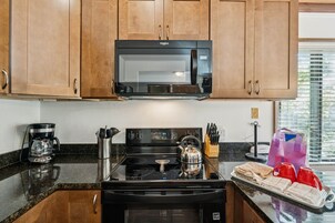 Et køkken med træskabe, mikrobølgeovn, komfur og kaffemaskine.