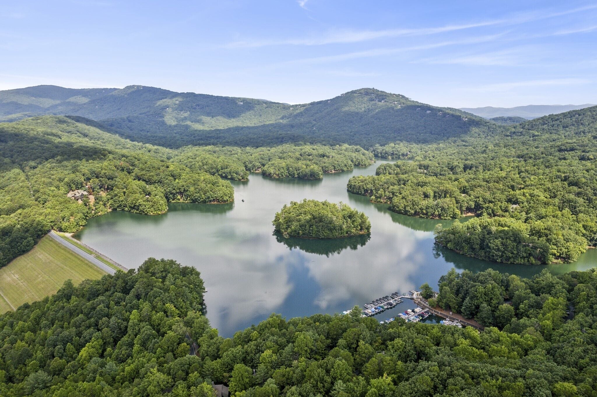 An aerial view of a lake surrounded by dense forest and hills.