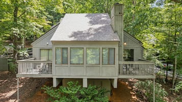 A two-story house with a balcony, surrounded by trees.