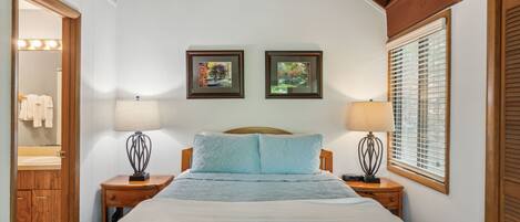 A bedroom with a bed, two bedside tables, a nightstand, a mirror, and two framed pictures on the wall.