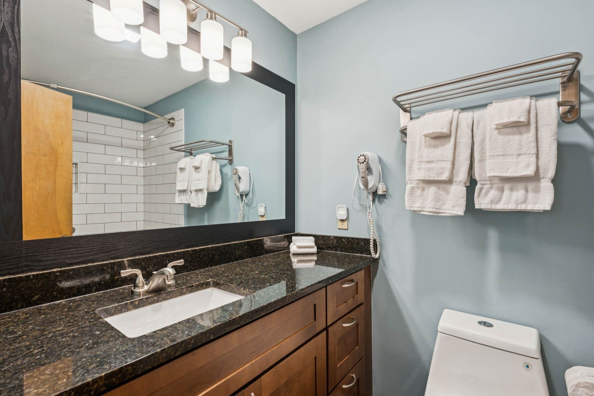 Une salle de bain équipée d’un lavabo, d’un miroir, d’un porte-serviettes et de toilettes.