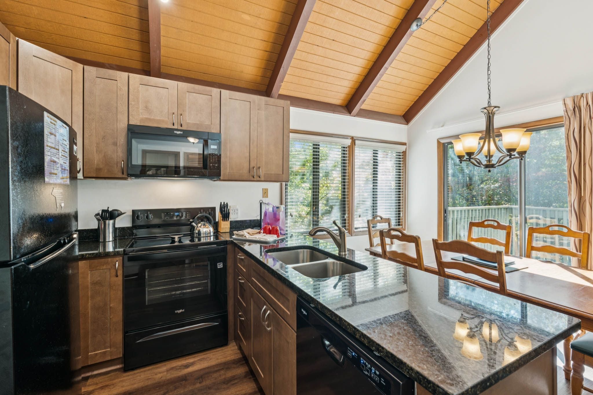 A modern kitchen with wooden cabinets, a black refrigerator, a stove, and a dishwasher.