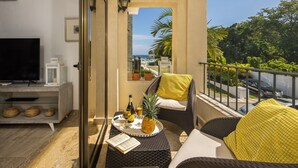 A balcony with wicker furniture, a TV, and a view of the sea. - Playa Laguna Beach Condos (Cabarete)