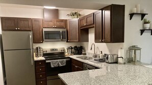 Eine Küche mit Holzausstattung, Edelstahlgeräten, Granit Arbeitsplatten und einer kleinen Kochinsel mit Spüle.