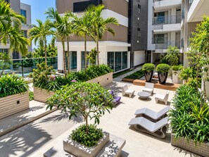 Un espace de détente extérieur moderne, doté de sièges et de jardinières, et entouré de bâtiments.