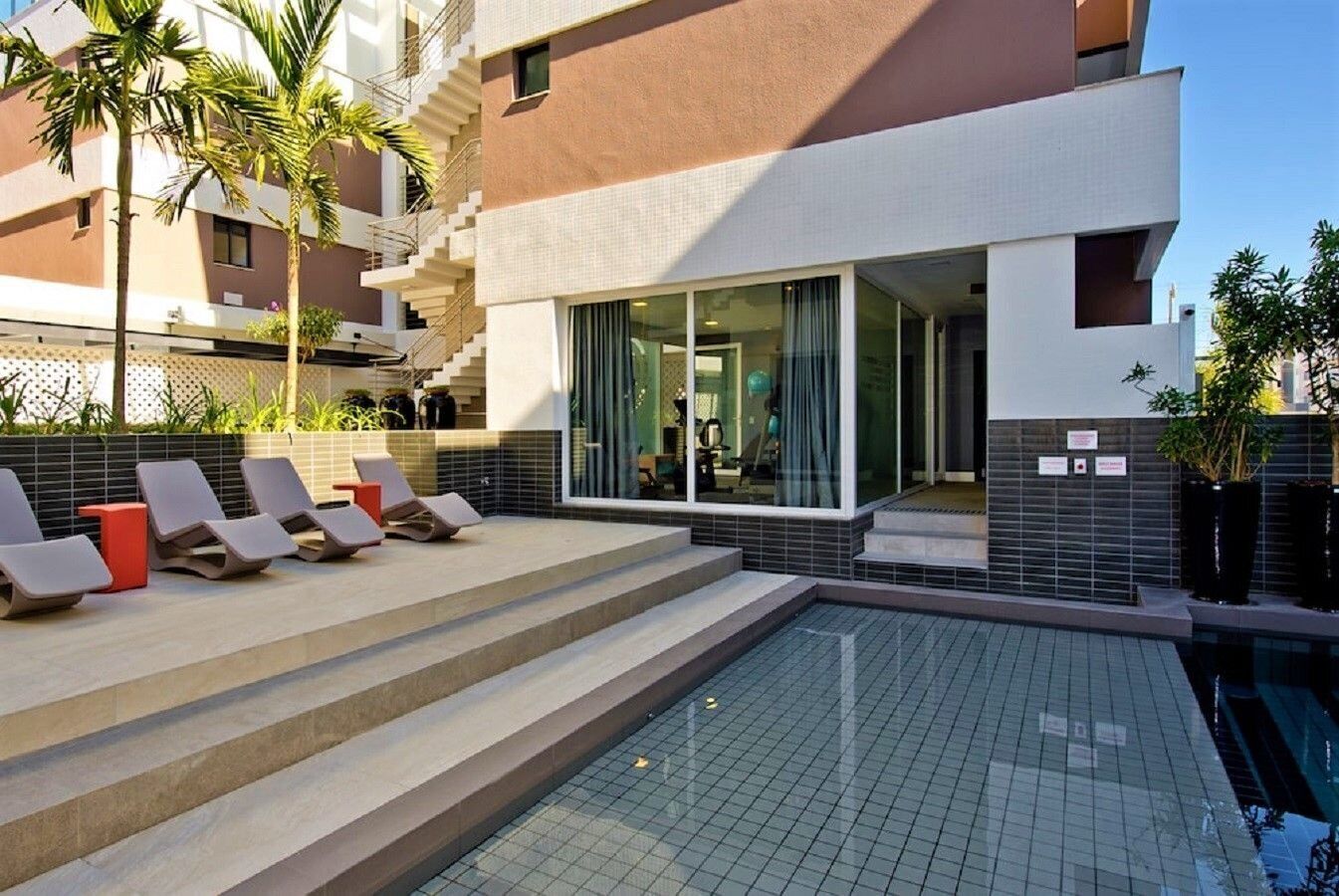 Una piscina al aire libre, sombrillas, tumbonas