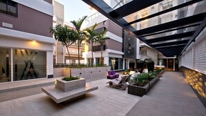 A modern outdoor area with seating, planters, and a glass ceiling structure. - Apartamento de Frente pro Mar - Campeche (Florianópolis)