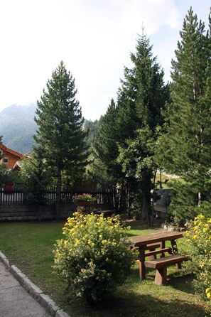 A picnic table surrounded by yellow flowers and tall trees in a park setting. - Alpha Hotel (Saas Grund)