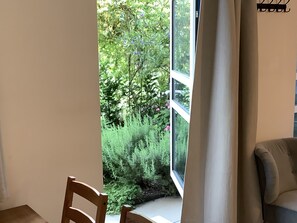 Ein Zimmer mit großem Fenster, einem Holzstuhl und einer Couch.
