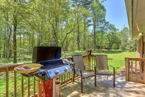 An outdoor deck with a grill, chairs, and a view of a forest. - Simple But Sweet Cottage House (Arden)