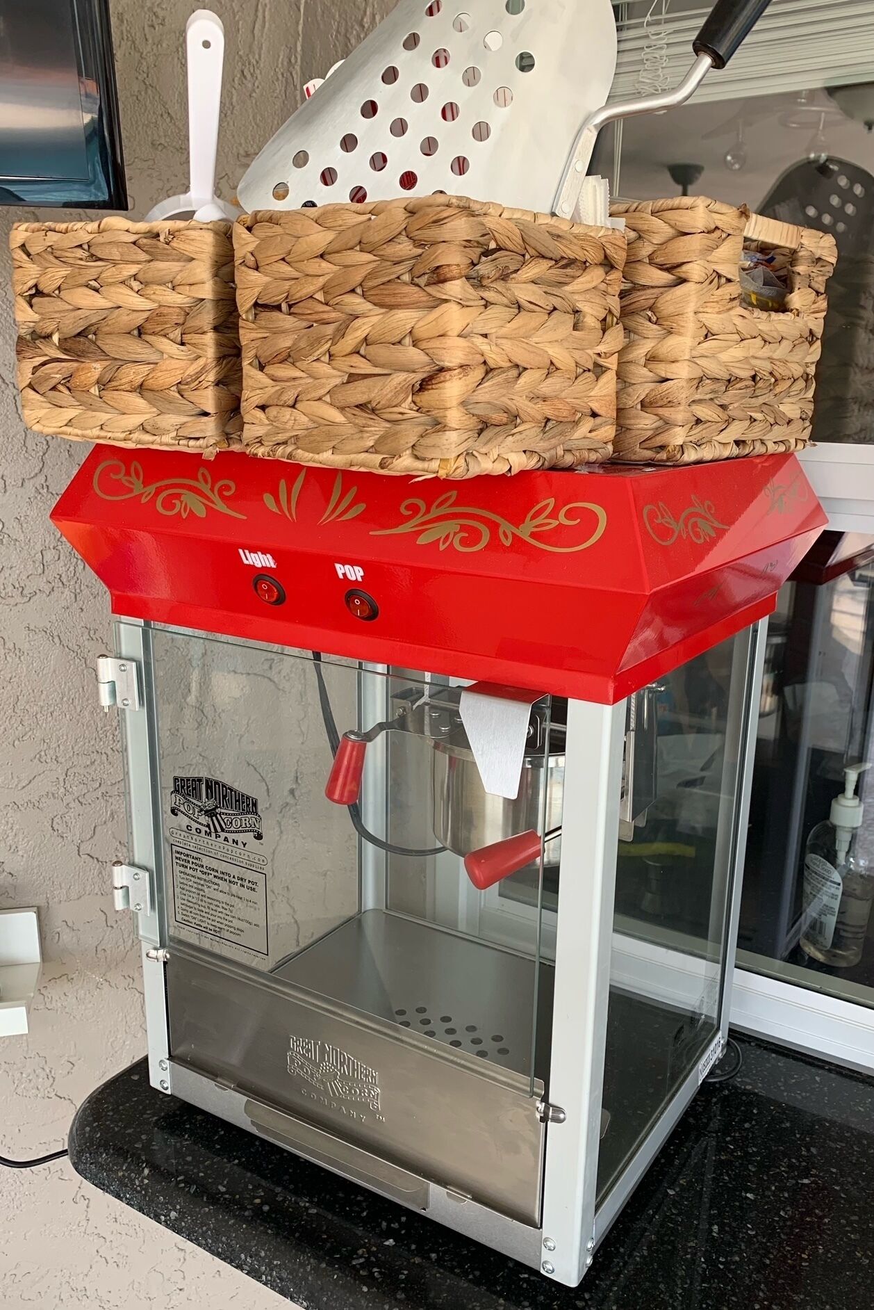 Eine Kaffeemaschine mit roter Oberseite und Glasfront auf einer schwarzen Arbeitsplatte.