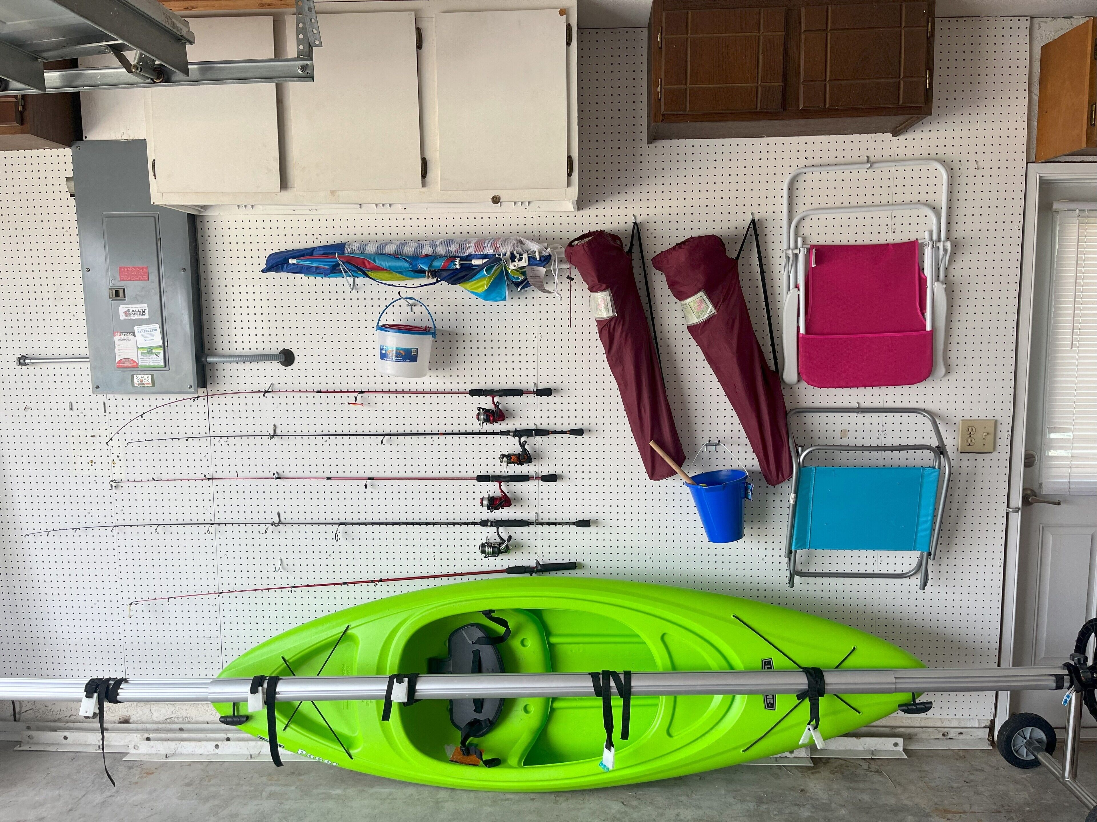 A pegboard wall with fishing rods, a kayak, and various fishing gear.