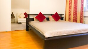 Een slaapkamer met een bed, nachtkastje, bank en een beeld.