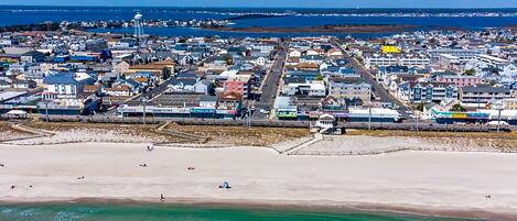 An aerial view of a coastal town with a beach, buildings, and a road.