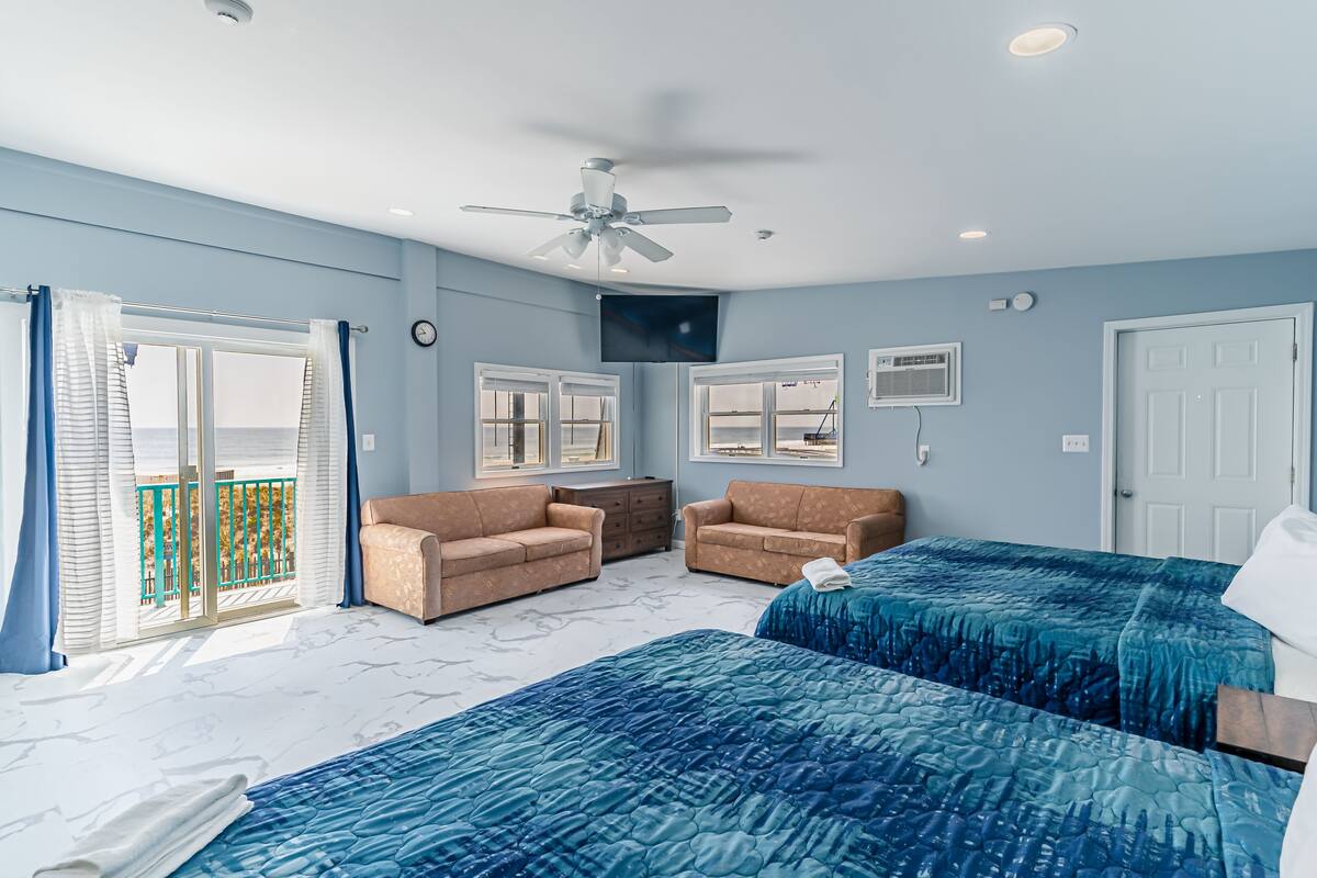 A bedroom with two beds, a ceiling fan, and a balcony with a view.