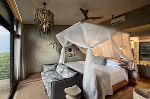 Un dormitorio con cama a dosel, una araña, un ventilador de techo y vistas al exterior.