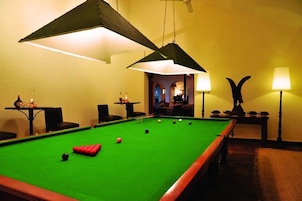 Una mesa de billar con bolas, una lámpara y un adorno en la pared.