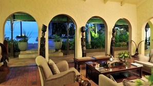 A spacious lobby with arched windows, comfortable seating, and a view of the sea. - Bumi Hills Safari Lodge (Bumi Hills)