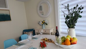 A dining table set with plates, cutlery, and a fruit bowl. - The Inn at Newton Highlands, boutique apartment-hotel (Newton)