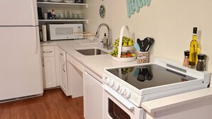 A compact kitchen with white appliances, a sink, and a countertop with a fruit bowl. - The Inn at Newton Highlands, boutique apartment-hotel (Newton)