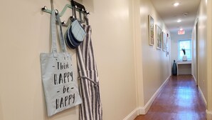 A hallway with a wooden floor, a striped robe, and a tote bag with a motivational quote. - The Inn at Newton Highlands, boutique apartment-hotel (Newton)