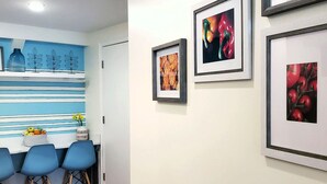A room with a blue and white striped wall, a white door, and three blue chairs. There are framed pictures on the wall. - The Inn at Newton Highlands, boutique apartment-hotel (Newton)