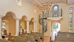 A church interior with pews, stained glass windows, a spiral staircase, and a chandelier. - L Ermitage Franschhoek Chateau Villas (Franschhoek)