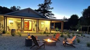 Ein Haus mit überdachter Veranda, Sitzgelegenheiten im Freien und einem Feuerkorb.