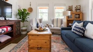 Ein Wohnzimmer mit einer Couch, einem Couchtisch, einem Fernseher und einer Pflanze.