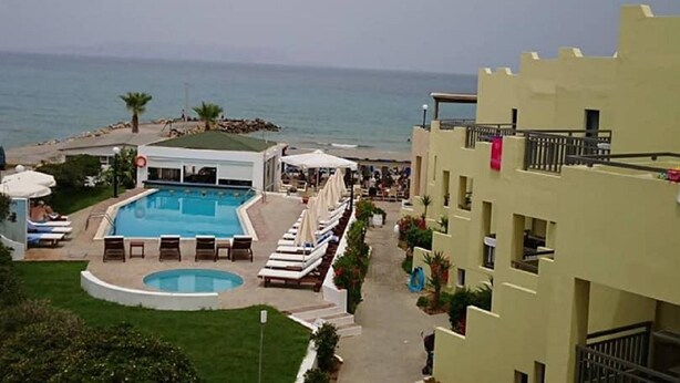 A hotel with a pool, lounge chairs, and a view of the sea. - Blue Sky Apartments (Hersonissos)