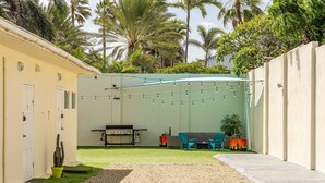 Ein Garten mit Grill, Stühlen und einer Kaktusstaude.