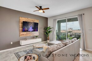 Relax in this stylish living room with a large flat-screen TV, comfortable sofa, and sliding glass door leading to a city view balcony.