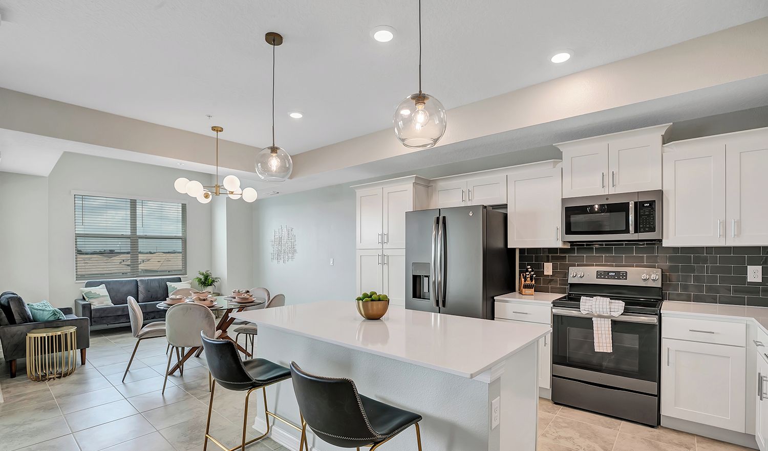 A modern kitchen with white cabinets, stainless steel appliances, and a central island with bar stools.