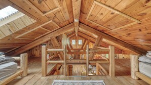 Un dormitorio en el ático con vigas de madera, un tragaluz y una cama con alfombra.