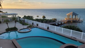 A pool area with a view of the sea, a gazebo, and a white fence. - Waterfront Bay House Rental (Port Isabel)