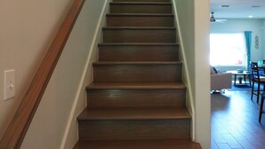 A wooden staircase with a handrail, leading to a room with a dining area and a ceiling fan. - Waterfront Bay House Rental (Port Isabel)