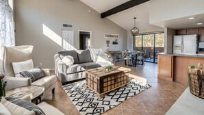 A spacious living room with a sofa, coffee table, and a dining area with a kitchen in the background. - Wake Up to Majestic Mountain Views in a Vaulted 2BR 2 BATH cozy getaway! (Tucson)