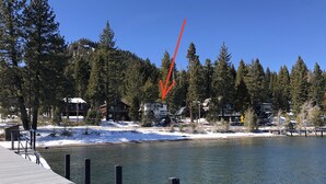 A lakeside property with a wooden dock, surrounded by snow-covered ground and dense evergreen trees. - Lake front chalet-incredible view, sleeps 12! (Homewood)