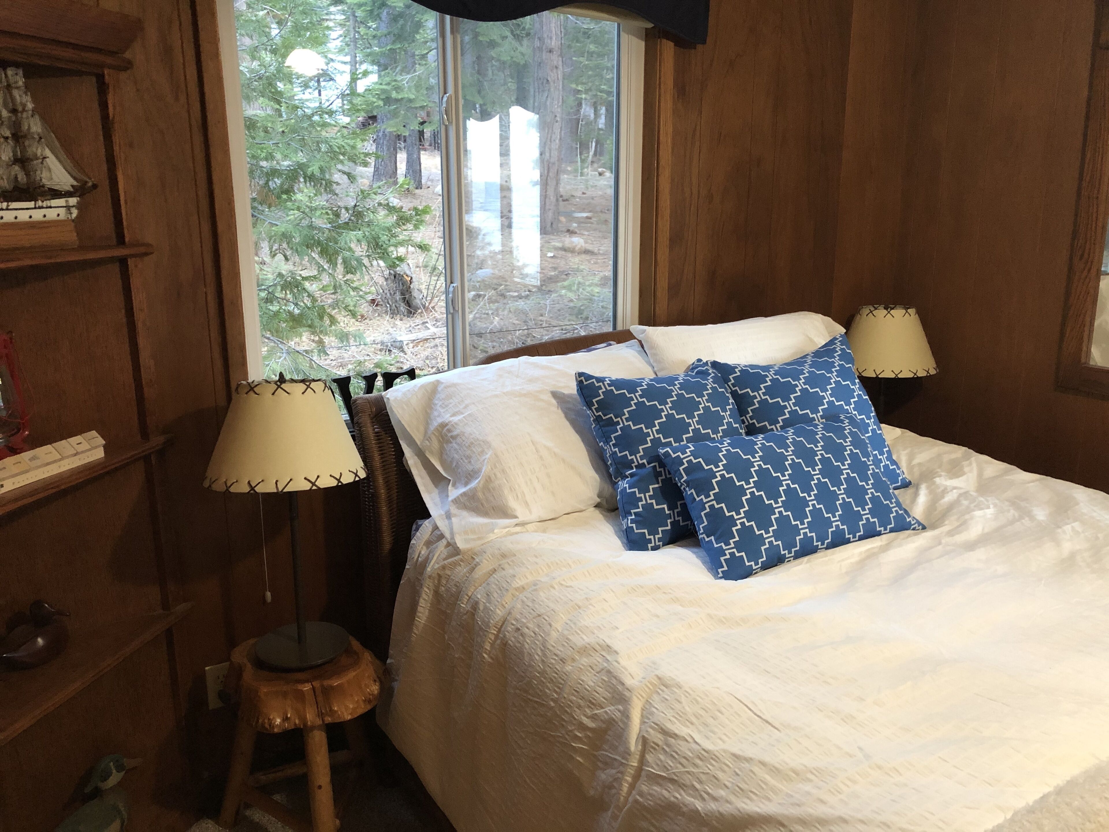A wooden room with a bed, a window, and a lamp.