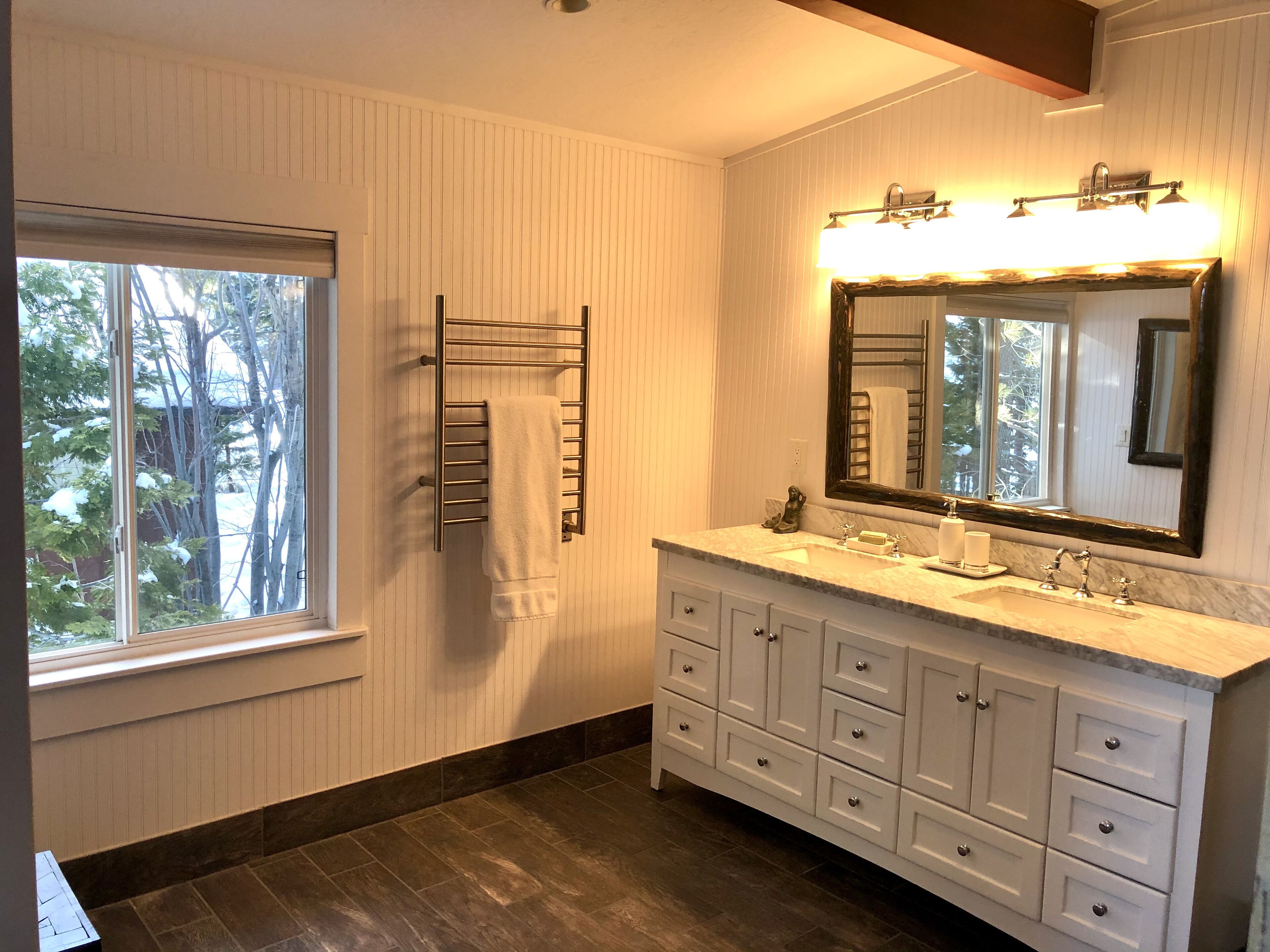 A bathroom with a large vanity, a mirror, and a towel rack.