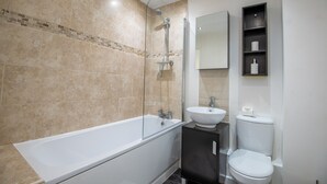 A modern bathroom with a bathtub, a sink, and a toilet. - No 10 (Mansfield)