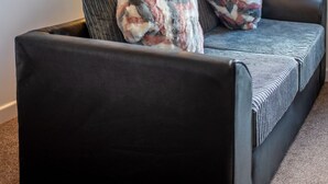 A cozy room with a sofa, two patterned throw pillows, a floor lamp, and a framed picture on the wall. - No 10 (Mansfield)