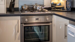 A modern kitchen with stainless steel appliances, including a stove, oven, and a range hood. - No 10 (Mansfield)