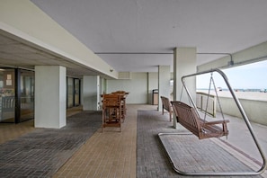 Uma área externa coberta com um balanço, uma mesa de madeira e cadeiras.
