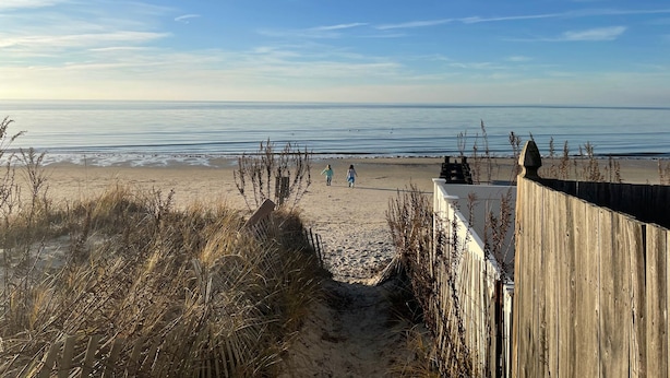 A beach with a wooden fence and a clear view of the ocean.