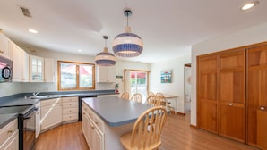A kitchen with wooden cabinets, a central island, and pendant lighting.