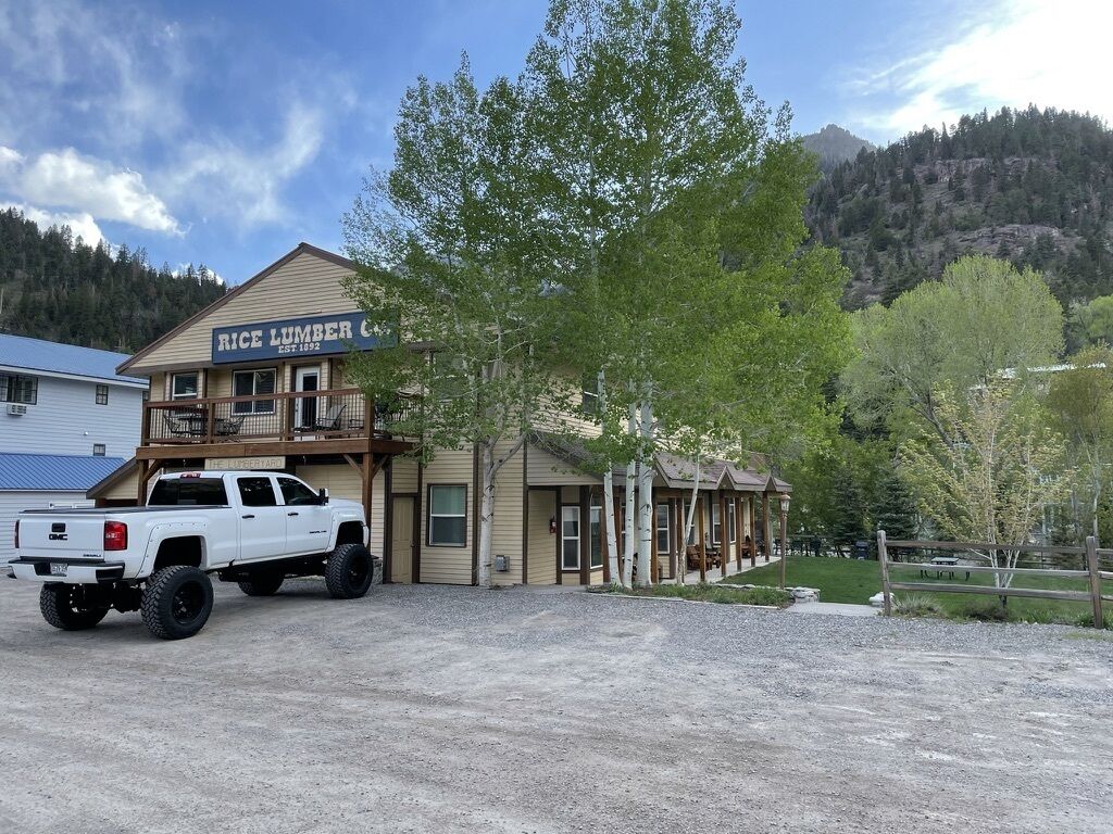 Un bâtiment à deux étages, sur lequel on peut lire l’inscription « Rice Lumber Co. », et un camionnette blanche garée devant.