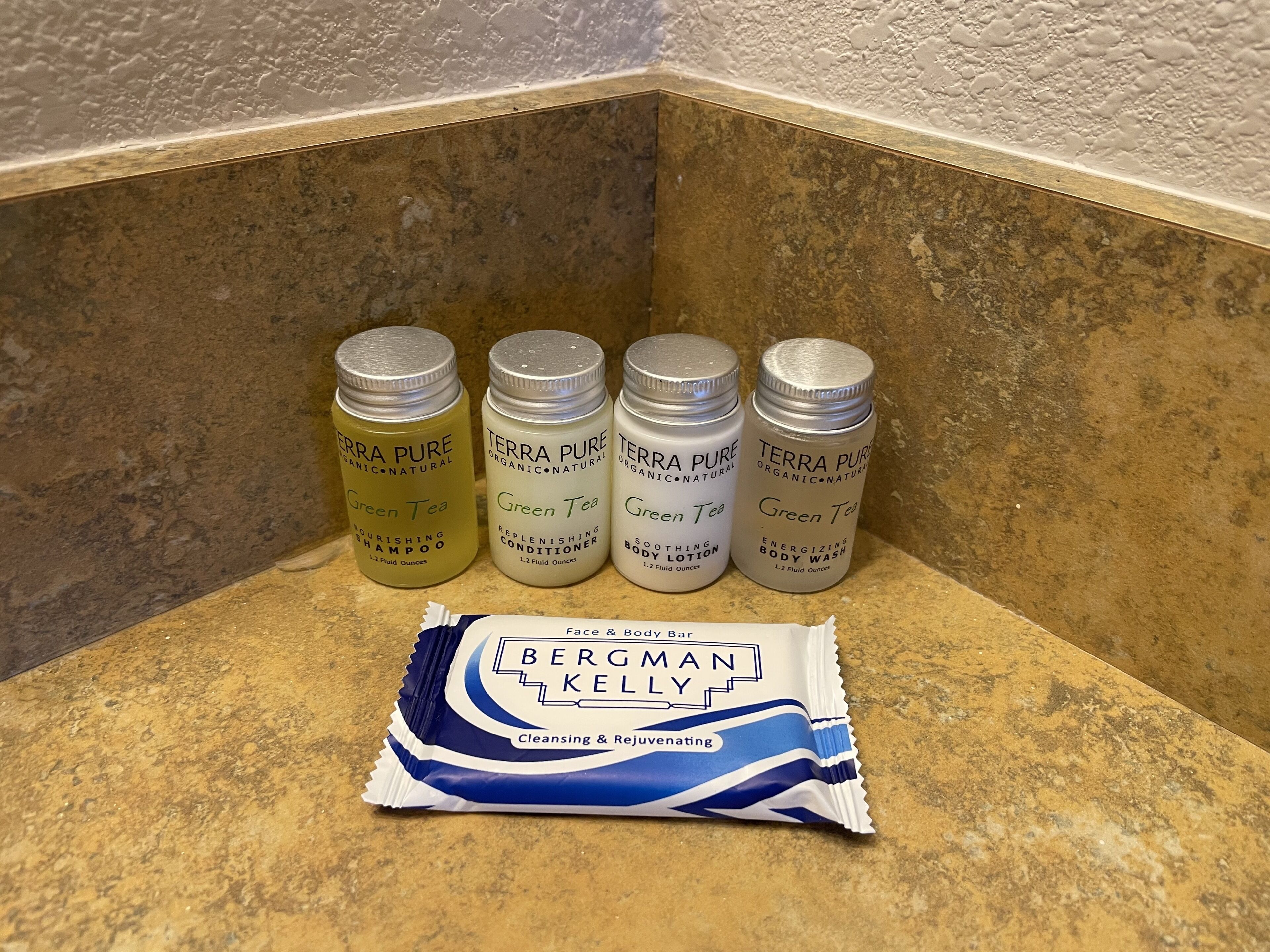 Four bottles of Terra Pure products and a Bergman Kelly cleansing bar on a countertop.