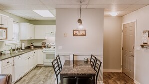 A kitchen with white cabinets, a marble countertop, and a dining table with four chairs. - Bay Breeze across from Waterfront (Eureka)